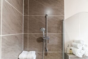 Une salle de bain moderne avec une douche à parois de verre, un porte-serviettes intégré et des serviettes soigneusement pliées.