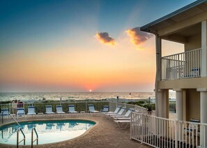 A pool area with lounge chairs and a view of the sunset over the ocean. - Condo On The Beach - Heated Pool - Self Check-in (Belleair Beach)