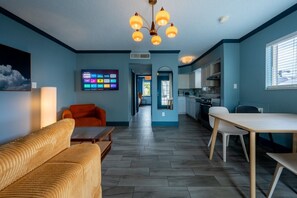 Un salon moderne avec un canapé, une table à manger et une cuisine en arrière-plan.