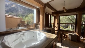 A bathroom with a large bathtub, wooden beams, and a view of mountains through large windows. - Casa Raiz -The Handmade House in Calca (Calca)