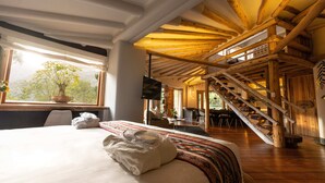 A hotel room with a large bed, a wooden staircase, and a view of the outdoors. - Casa Raiz -The Handmade House in Calca (Calca)