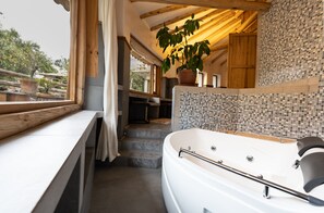 A modern bathroom with a large bathtub, a potted plant, and a view of the outdoors. - Casa Raiz -The Handmade House in Calca (Calca)