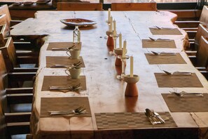 A wooden dining table set with candles, cutlery, and napkins. - Casa Raiz -The Handmade House in Calca (Calca)