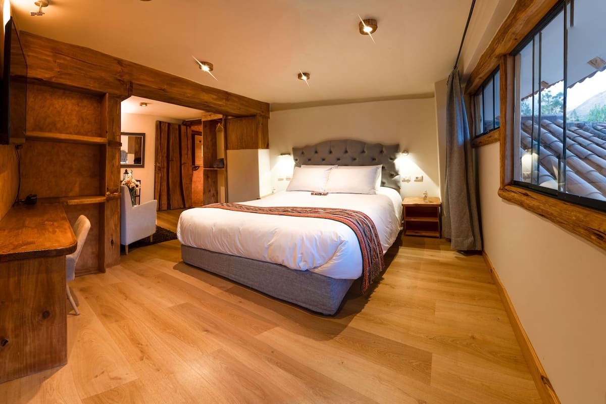 A bedroom with a large bed, wooden furniture, and a window with a view.