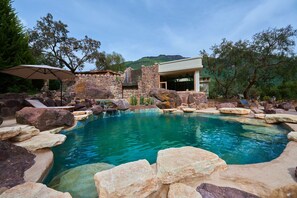 A pool surrounded by rocks and a stone building with a glass door. - Casa Raiz -The Handmade House in Calca (Calca)