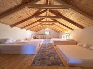 Acogedor dormitorio en el ático con vigas de madera, dos camas, un televisor y un ventanal.