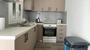 Une cuisine de taille réduite, dotée d’un four encastré, d’un évier et de placards.