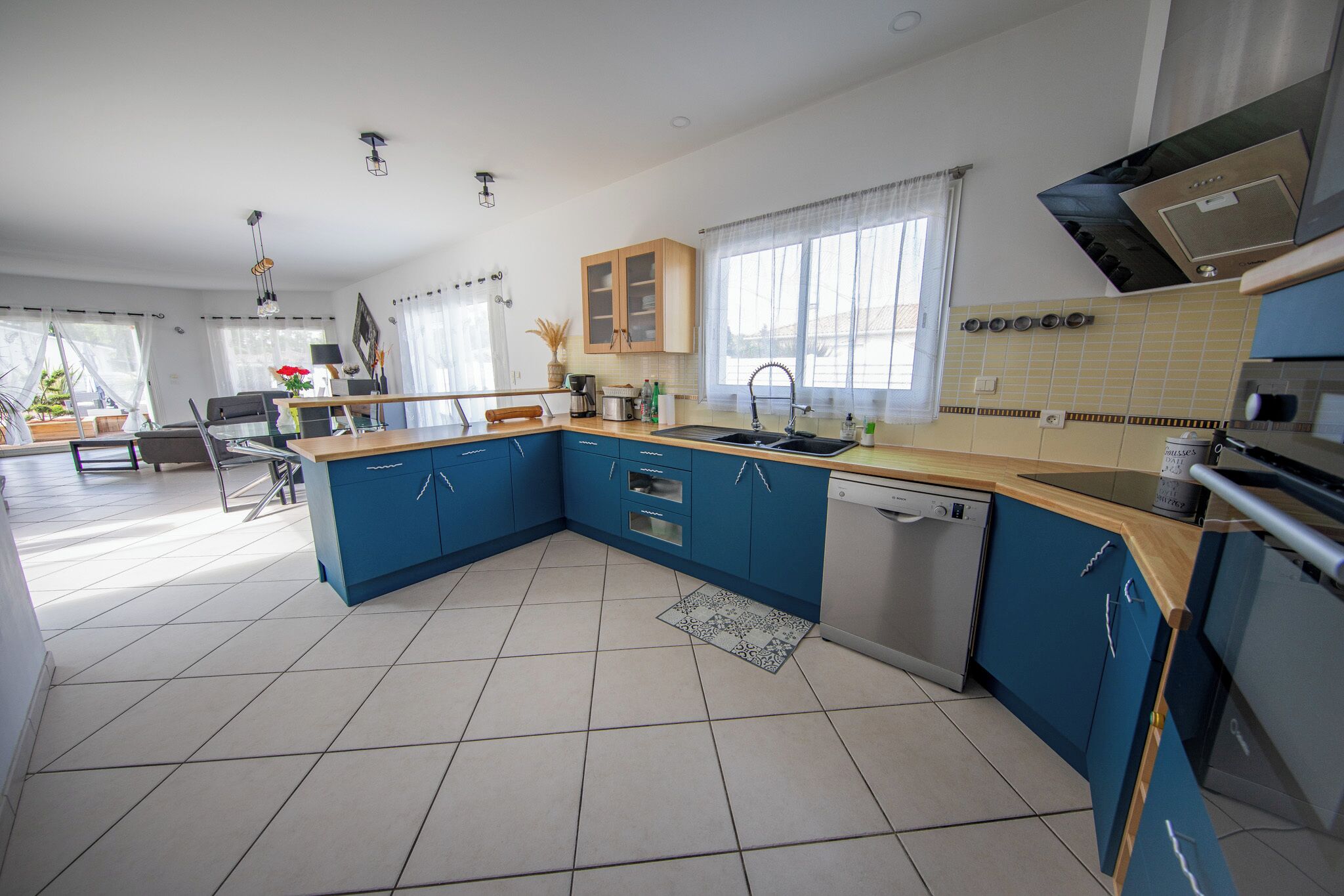 A modern kitchen with blue cabinets, a dishwasher, and a large window.