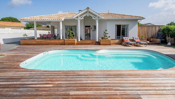 Une maison avec une piscine, un patio couvert avec des chaises et une statue de Bouddha.