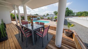 Un espace extérieur abrité comprenant une piscine, une terrasse en bois et des sièges.