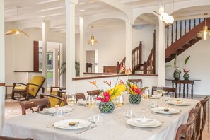 Un coin repas avec une table mise pour le repas, des chaises et des vases décoratifs ornés de fleurs.
