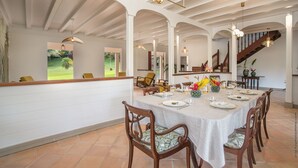 A dining area with a long table set for a meal, surrounded by wooden chairs. - Habitation La Thibault Exceptional estate in the heart of Martinique (Gros-Morne)