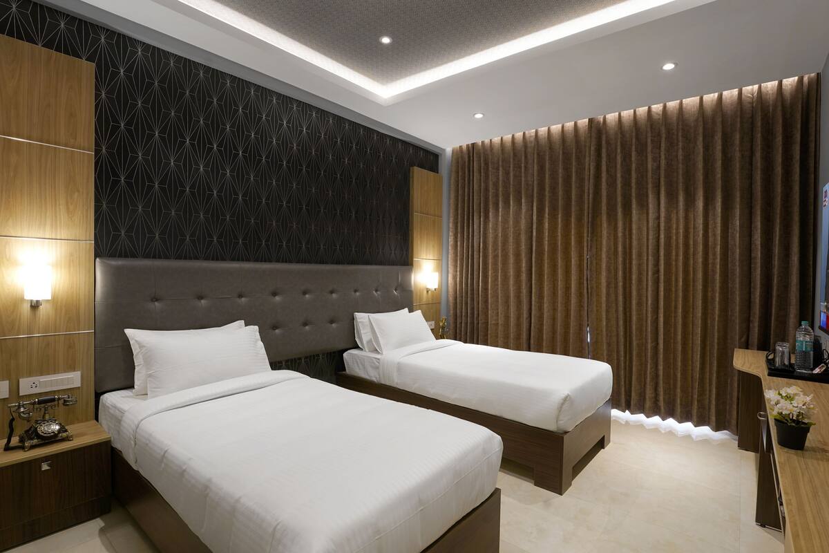 Une chambre d’hôtel avec deux lits, une télévision, un bureau et un mur orné de motifs géométriques.