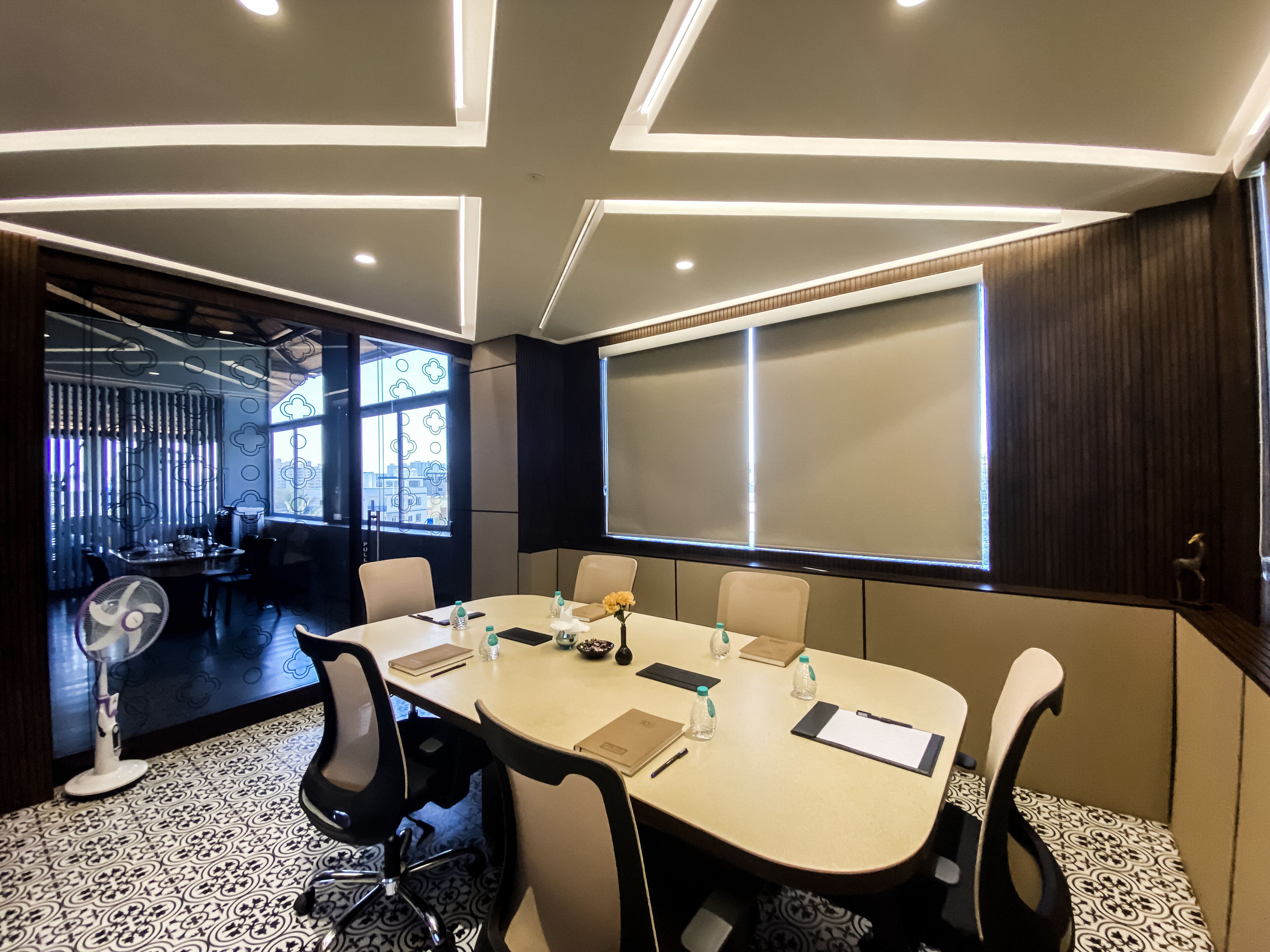 A conference room with a large table, chairs, and a projector screen.