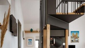 A modern living space with a staircase, a dining area, and a kitchen in the background. - Villa Magliolo (Cefalù)
