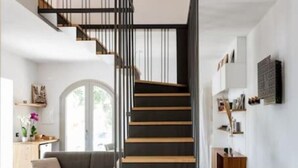 A modern staircase with black and wooden steps, a black railing, and a pendant light. - Villa Magliolo (Cefalù)