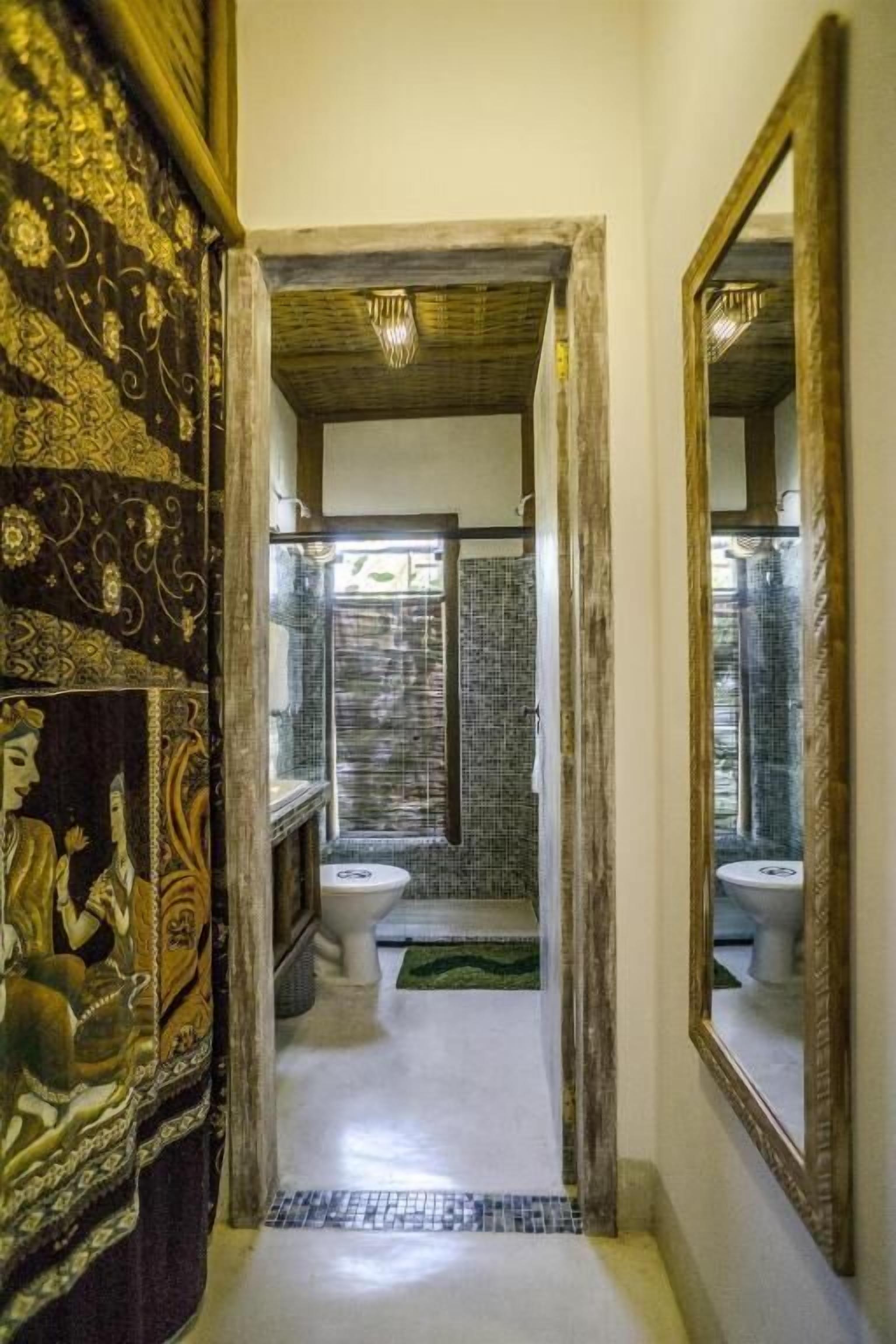 A narrow hallway leading to a bathroom with a tiled shower area and a toilet.