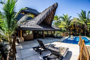 Un resort con piscina, sillas de descanso y construcciones de techo de paja.