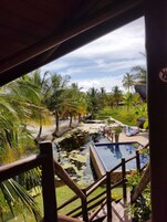 Vista de un área de piscina con fuente de agua, rodeada de palmeras y césped.