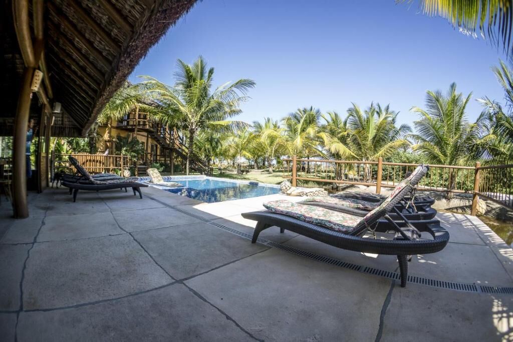 A pool area with lounge chairs and a thatched roof structure.