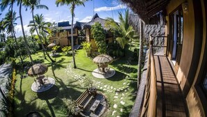 A tropical resort with thatched-roof structures, palm trees, and a well-maintained garden.