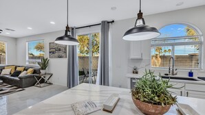 Een moderne keuken met een marmeren aanrecht, een groot raam met zonwering en een potplant op het aanrecht.
