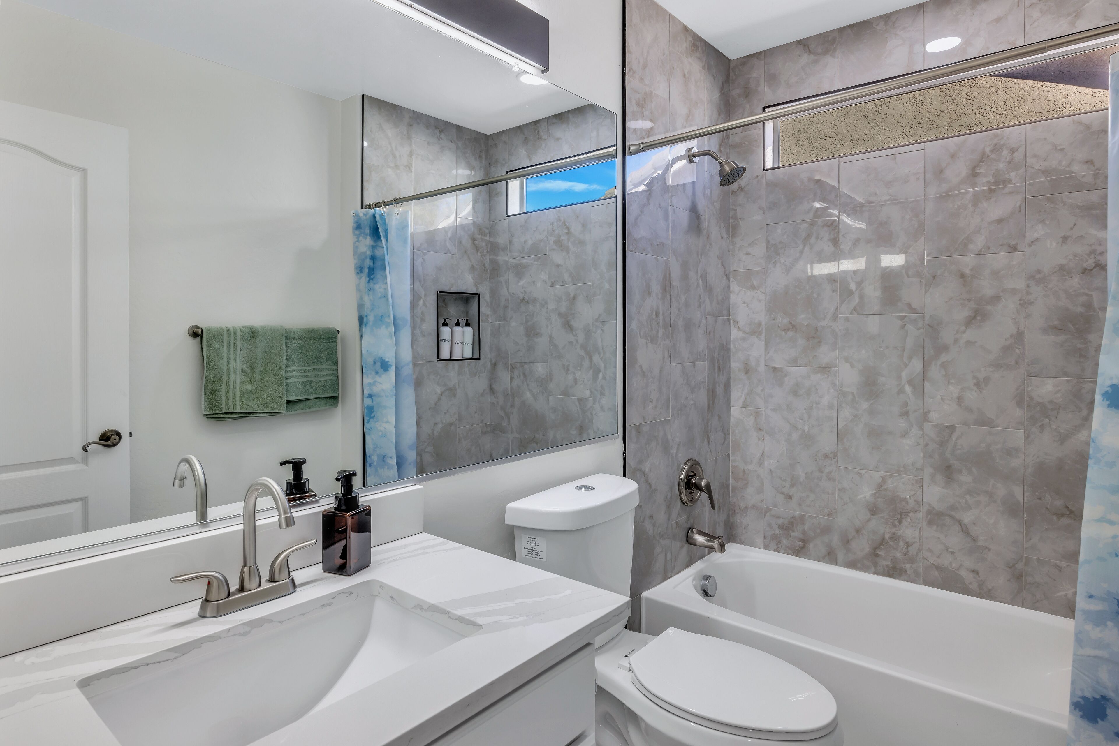 A modern bathroom with a dual sink vanity, a toilet, and a bathtub.