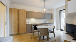 Una cocina moderna con armarios de madera, una mesa de comedor redonda y un televisor sobre una encimera blanca.