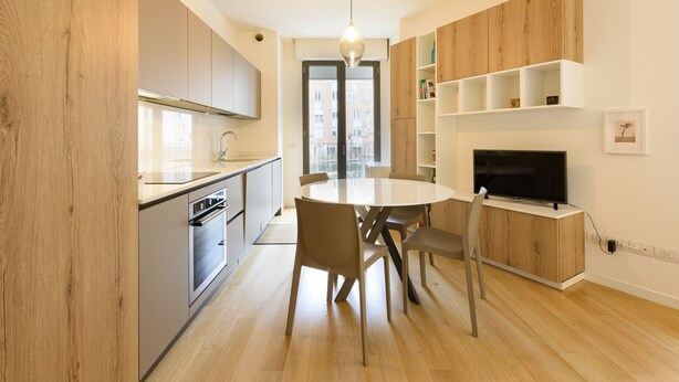 Una cocina moderna con comedor, armarios de madera y un televisor de pantalla plana.