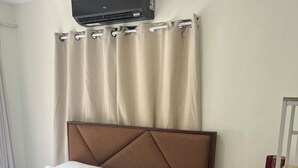 A neatly made bed with a brown headboard, a rolled towel, and a white pillow. - Comfy Family Condo in Resort Condo! (Davao City)