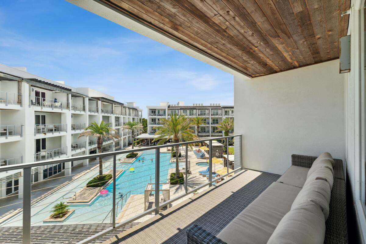 Een balkon met uitzicht op een zwembad en omliggende gebouwen.