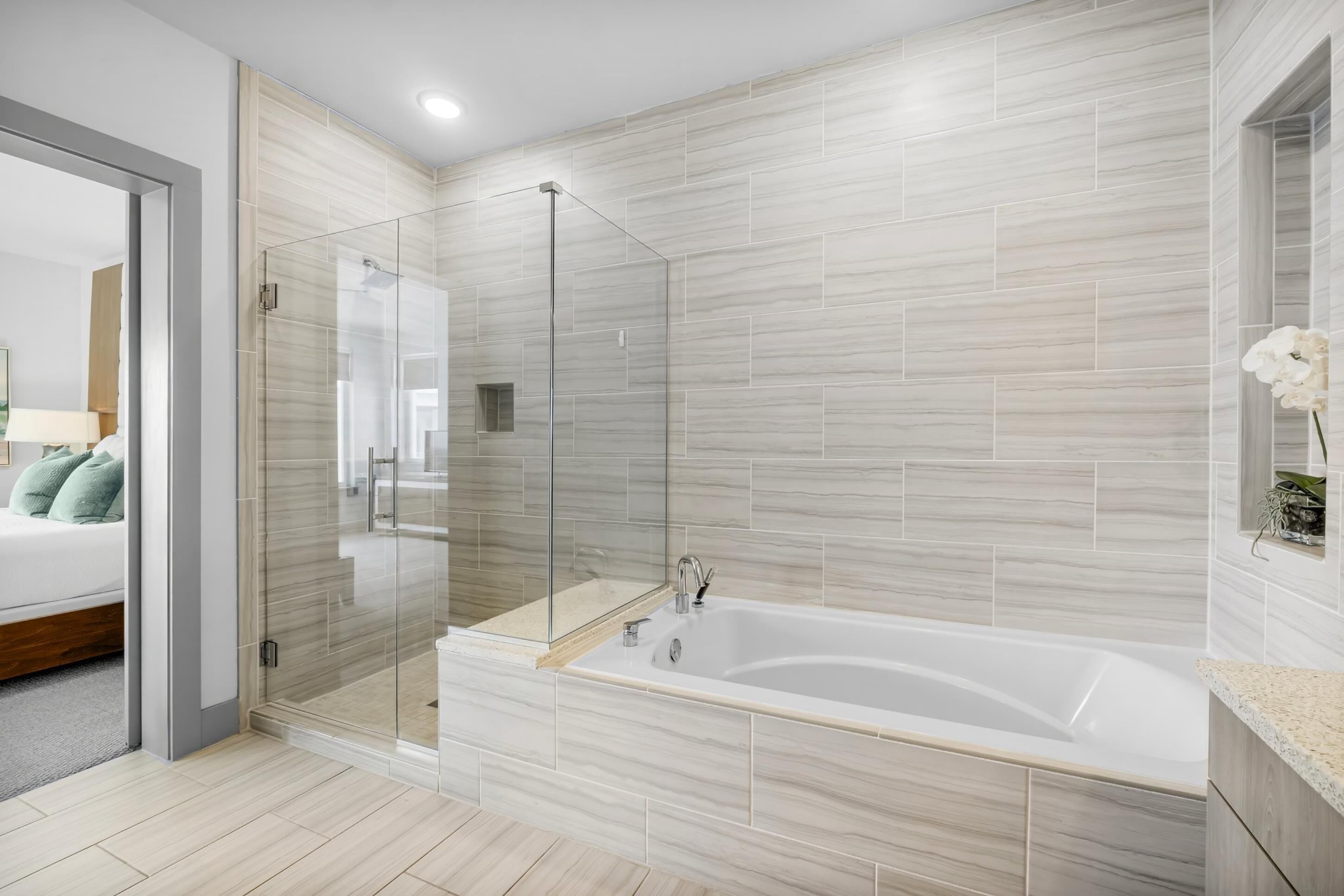 A modern bathroom with a glass-enclosed shower, a freestanding bathtub, and a tiled floor.