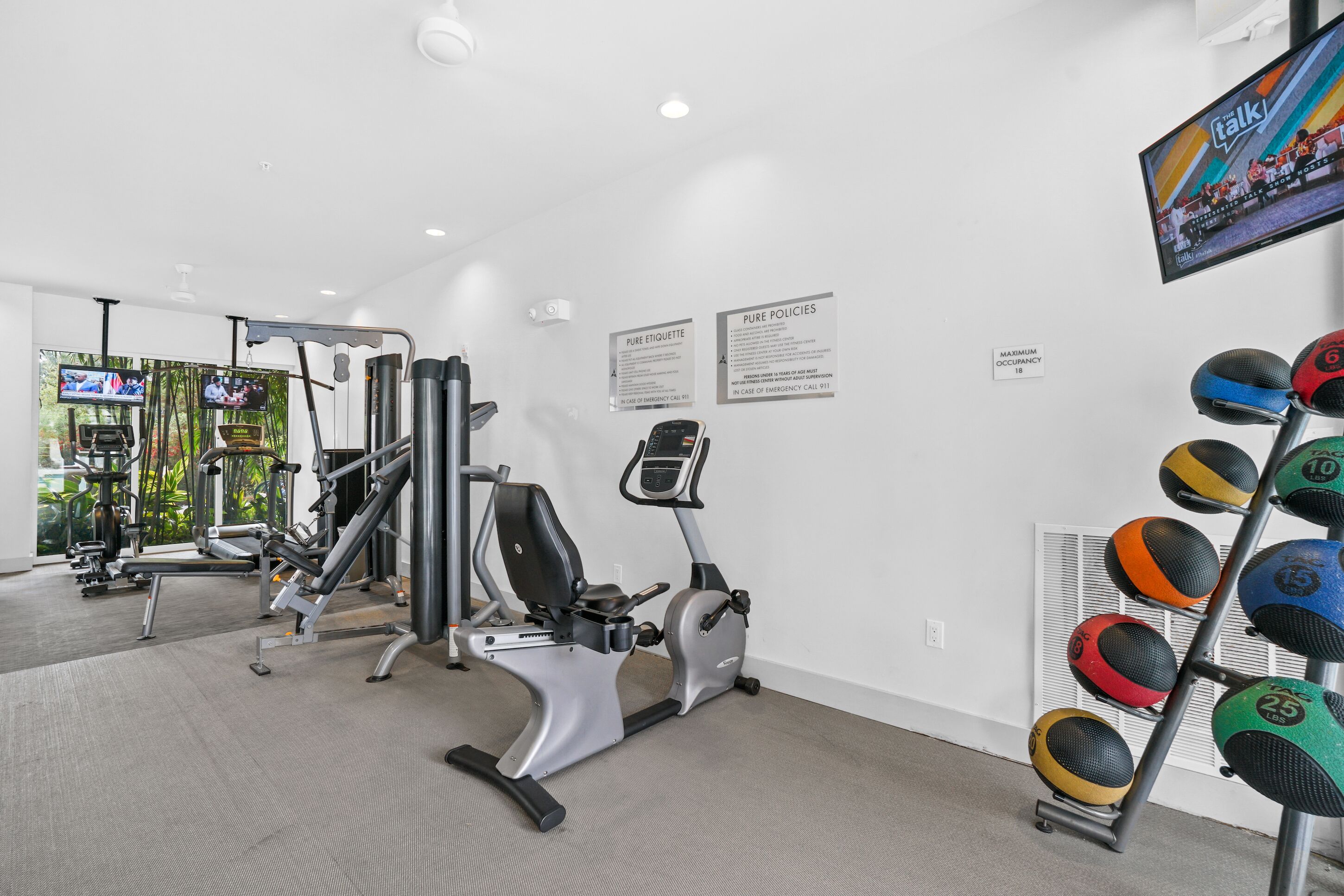 Una palestra con attrezzature per esercizi, una televisione e un cartello appeso al muro.
