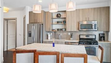A modern kitchen with wooden cabinets, stainless steel appliances, and a granite countertop.