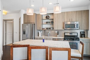 A modern kitchen with wooden cabinets, stainless steel appliances, and a granite countertop.