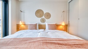 Quarto moderno com uma cama grande, duas luminárias de cabeceira e vista para o exterior.