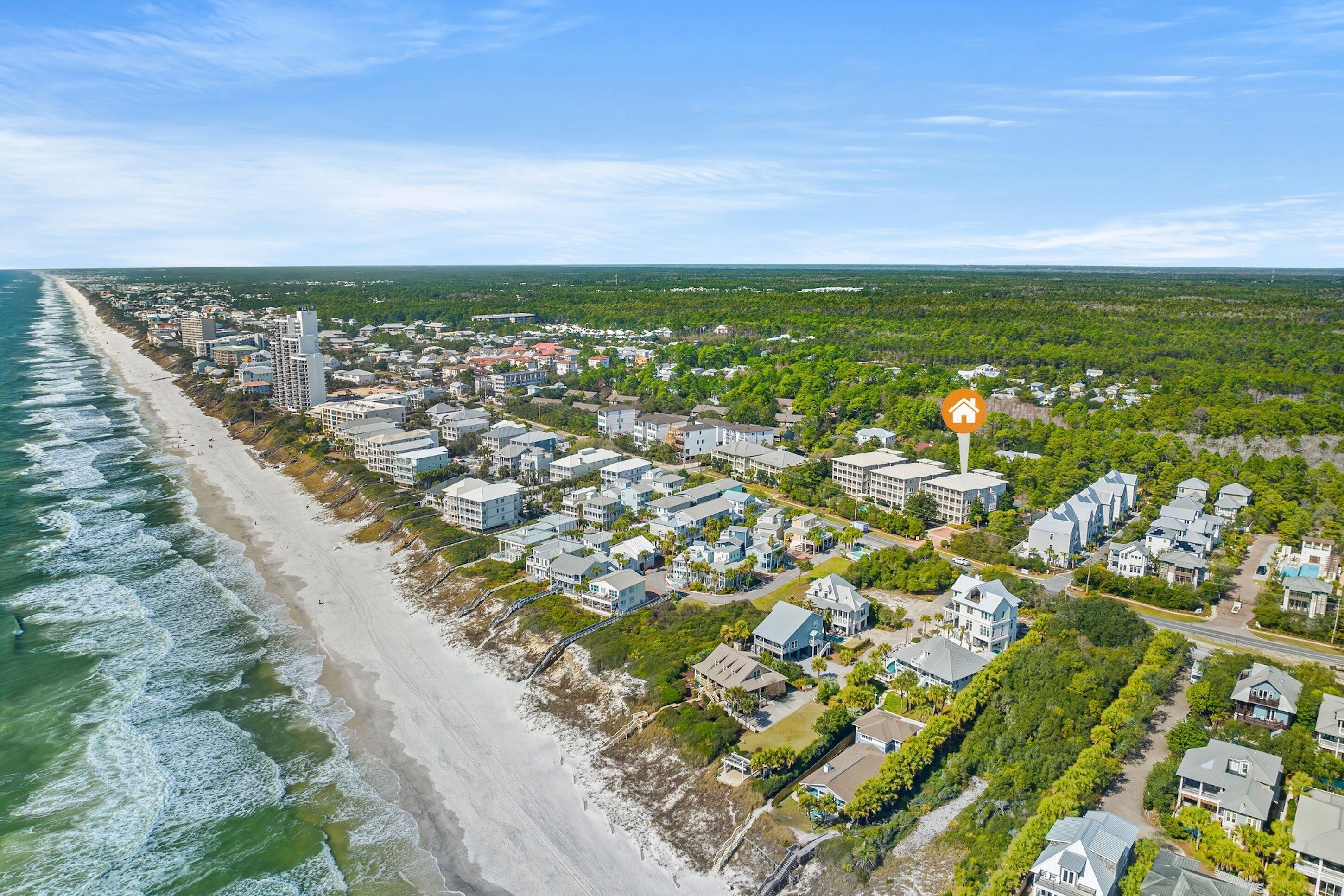 Luchtbeeld van een kustwoongebied met een strand, huizen en een opvallend hotelschilt.