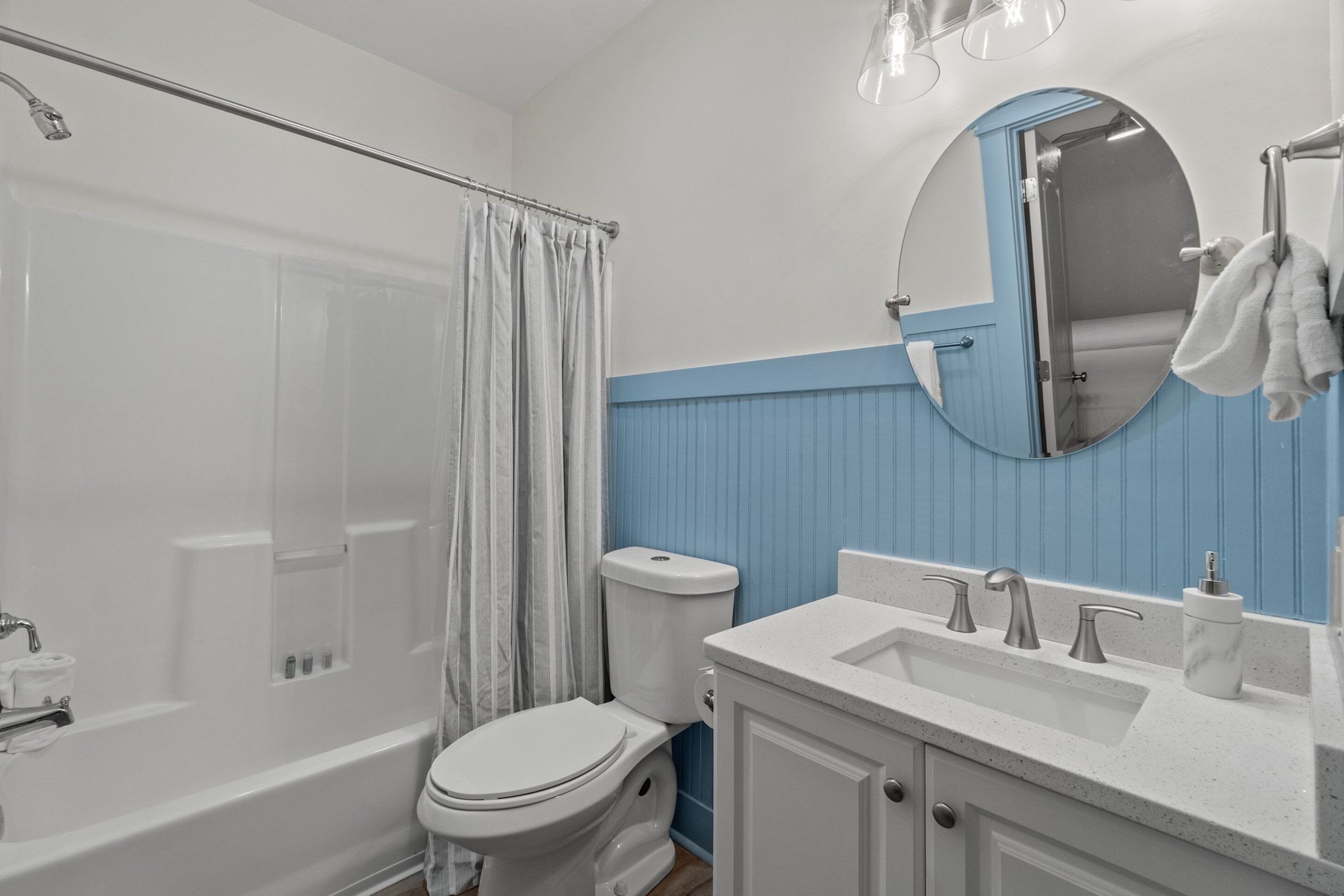 A bathroom with a bathtub, toilet, sink, and a mirror.
