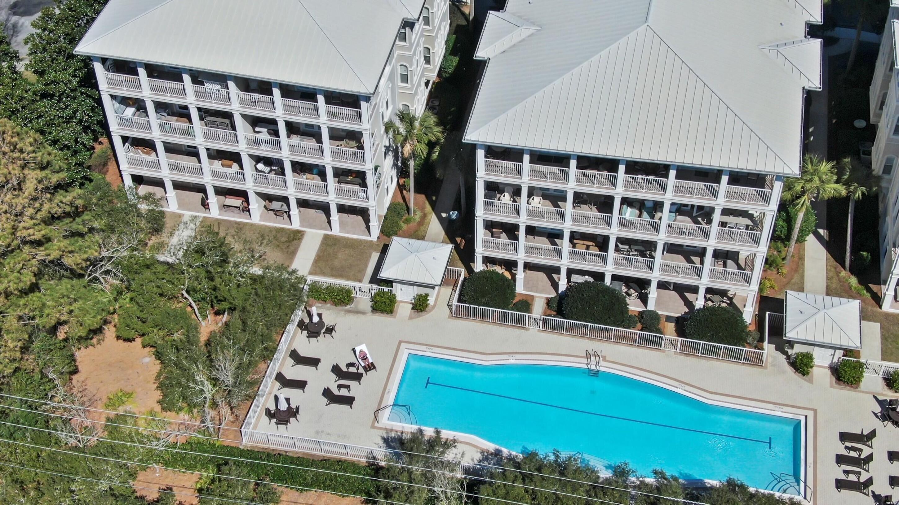 A multi-story hotel with balconies, a swimming pool, and outdoor seating areas.