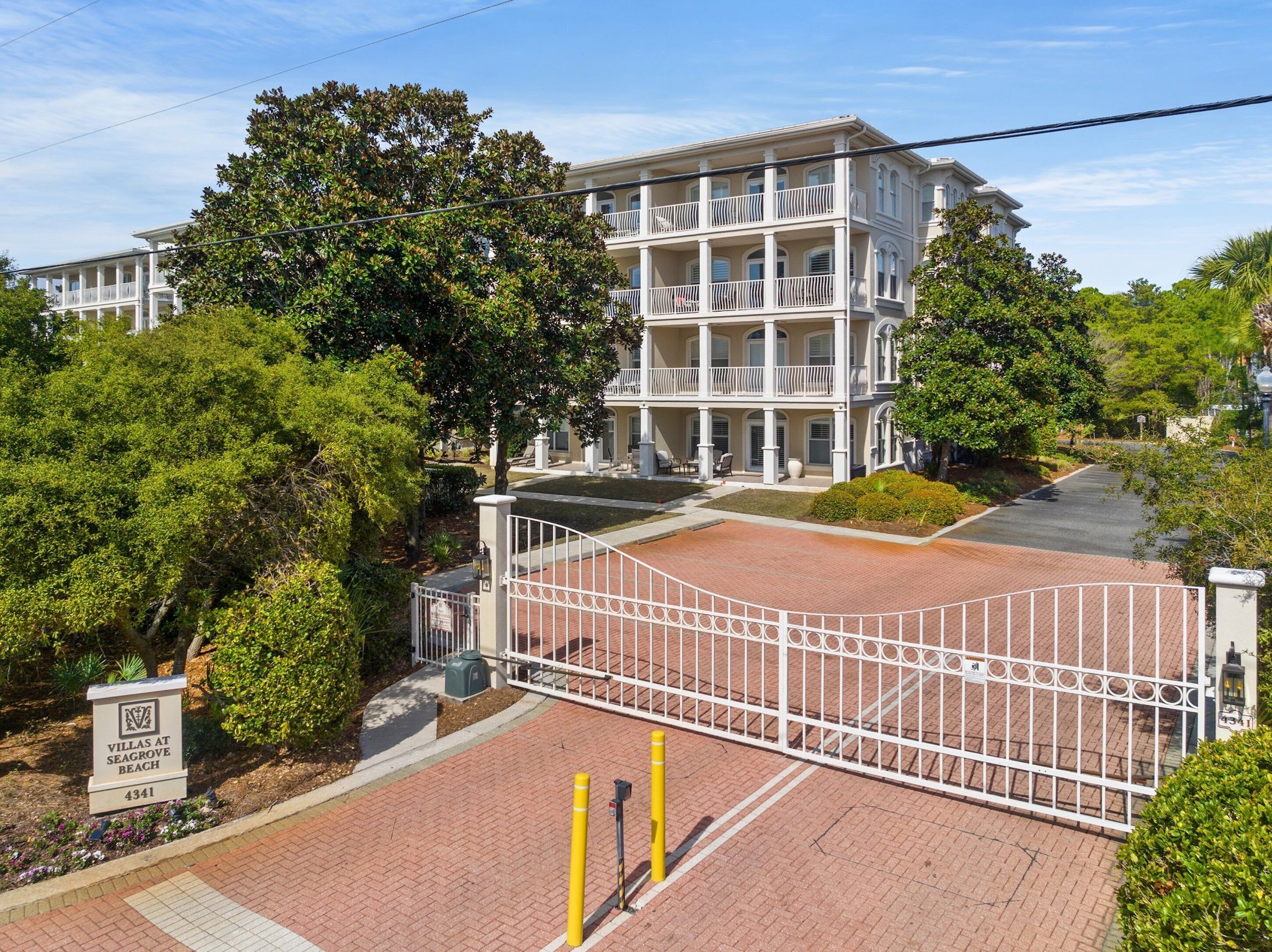 A multi-story building with a gated entrance, surrounded by lush greenery.