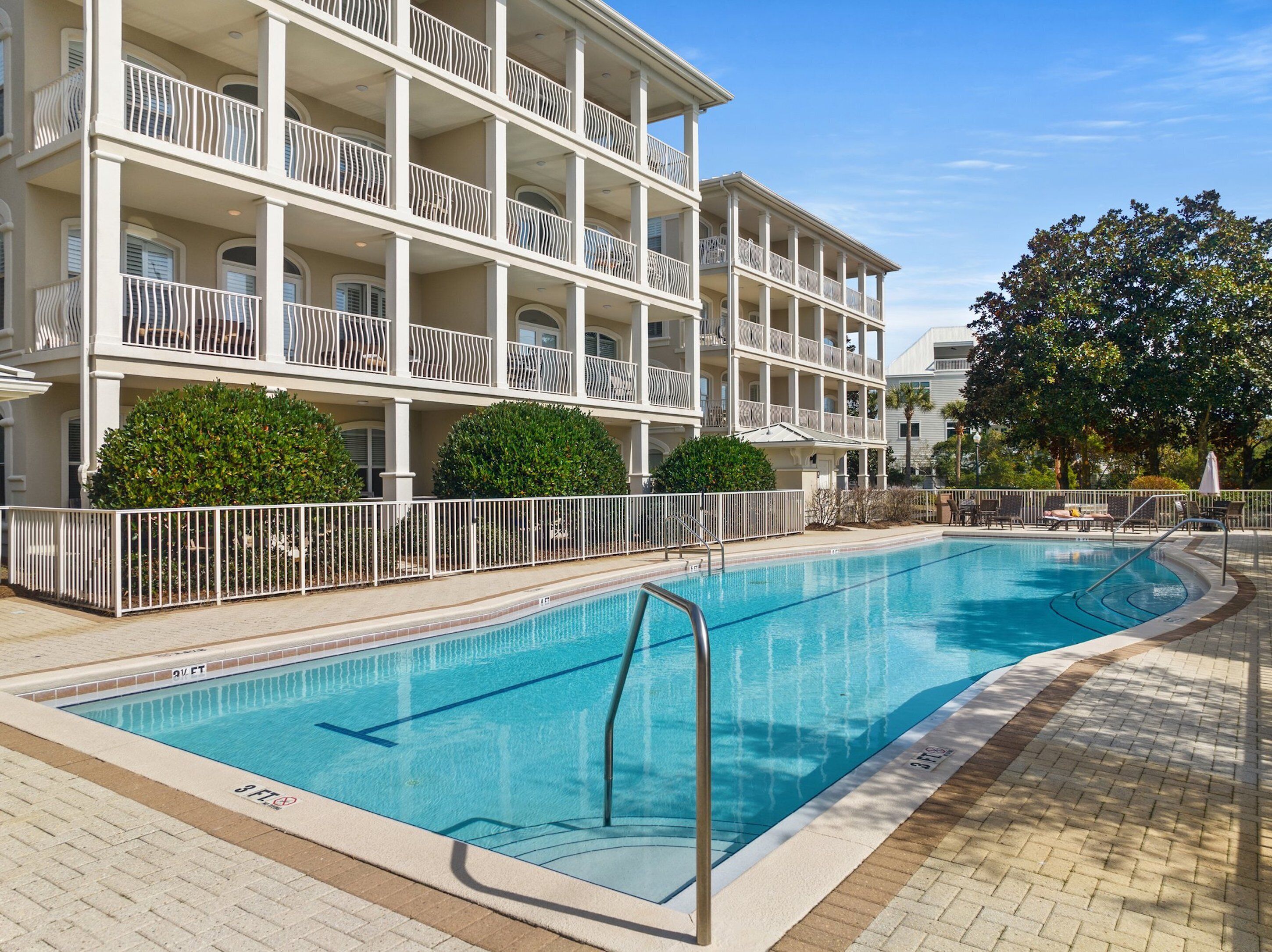 A swimming pool adjacent to a multi-story building with balconies.