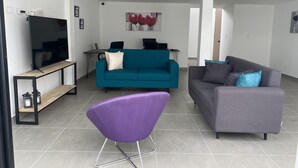 A modern living room with a teal sofa, a purple chair, and a grey sofa. - House F - Beautiful House Traditional Facade - Modern Interior (Filandia)