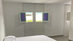 A bedroom with a bed, a nightstand, and a window with a view of greenery. - House F - Beautiful House Traditional Facade - Modern Interior (Filandia)