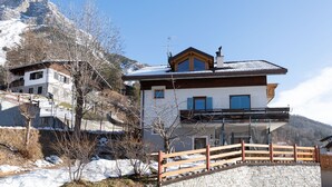 A two-story house with a stone facade, wooden balcony, and a view of a mountainous landscape. - Ripa Fontana 1 Mono - Studio Apartment, Sleeps 2 (Valdidentro)
