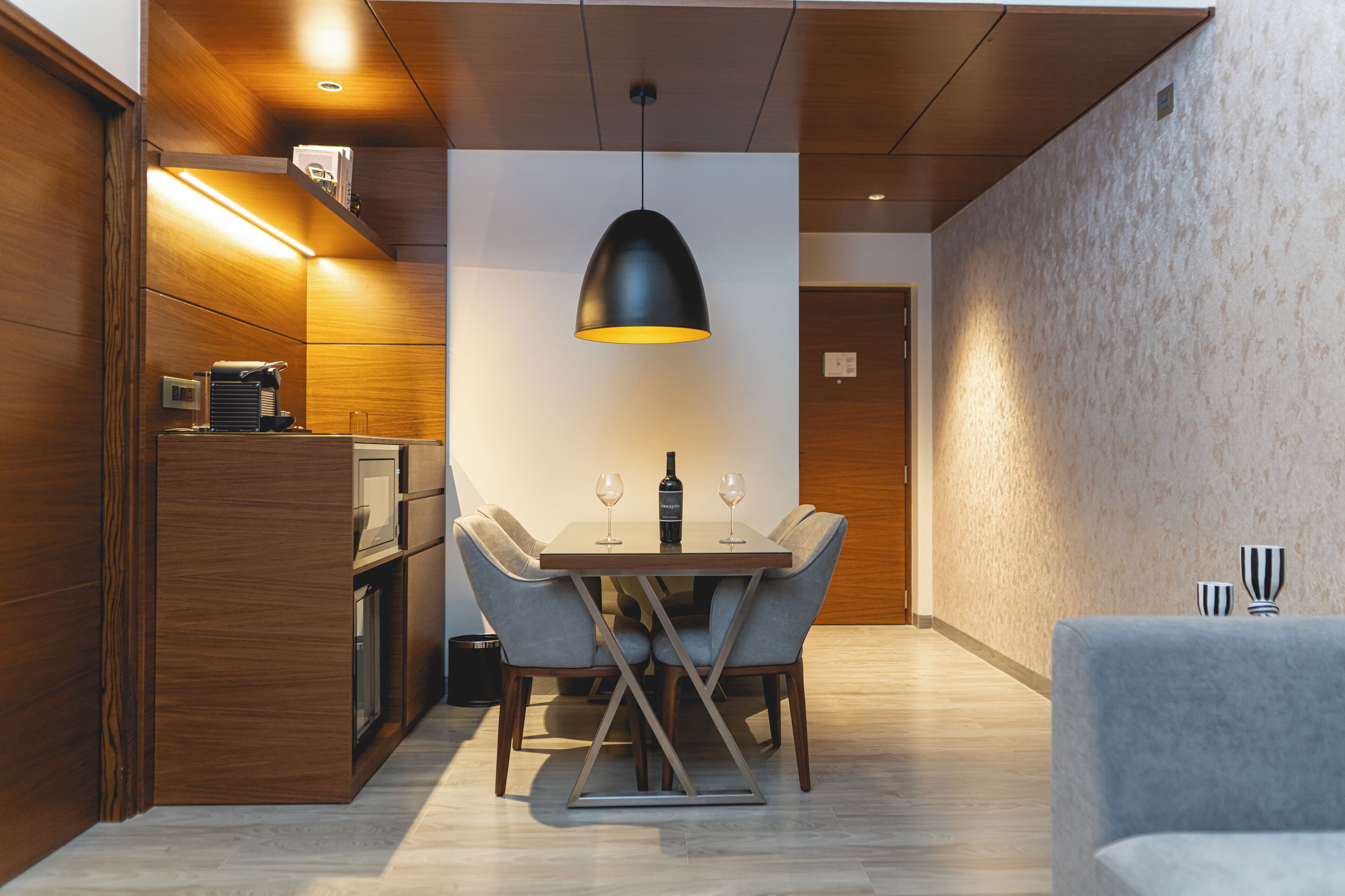A modern dining area with a wooden table, four chairs, and a pendant light.