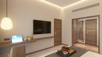 A modern hotel room with a bed, a desk with a laptop, a TV, and a wardrobe.