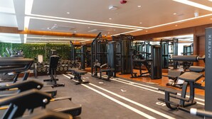 Een moderne sportschool met diverse fitnessapparaten, waaronder loopbanden, krachttoestellen en gewichten.