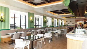 Een modern restaurant met hoge tafels en zitjes, groene verticale panelen en hangplanten.