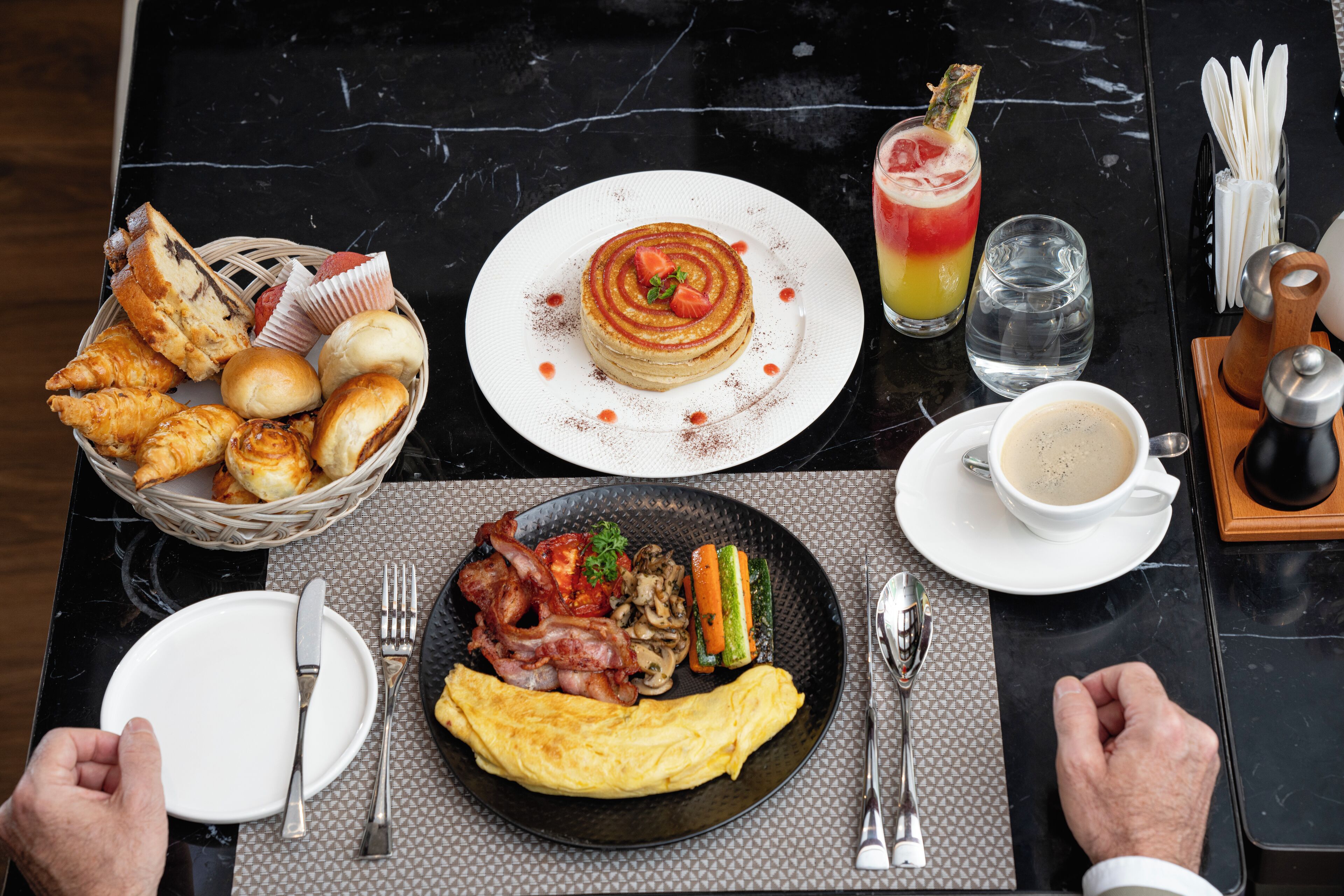 Ein Frühstückstisch mit verschiedenen Speisen, darunter Pfannkuchen, Eier und einem Getränk.