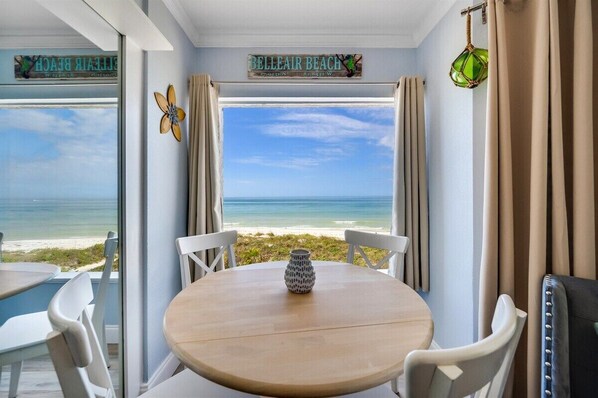 Enjoy stunning views of Belleair Beach from this room, featuring a round table and chairs, a vase, and a hanging light fixture.